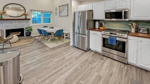 Una cocina moderna con muebles blancos, electrodomésticos de acero inoxidable y una zona de comedor con sillas azules.