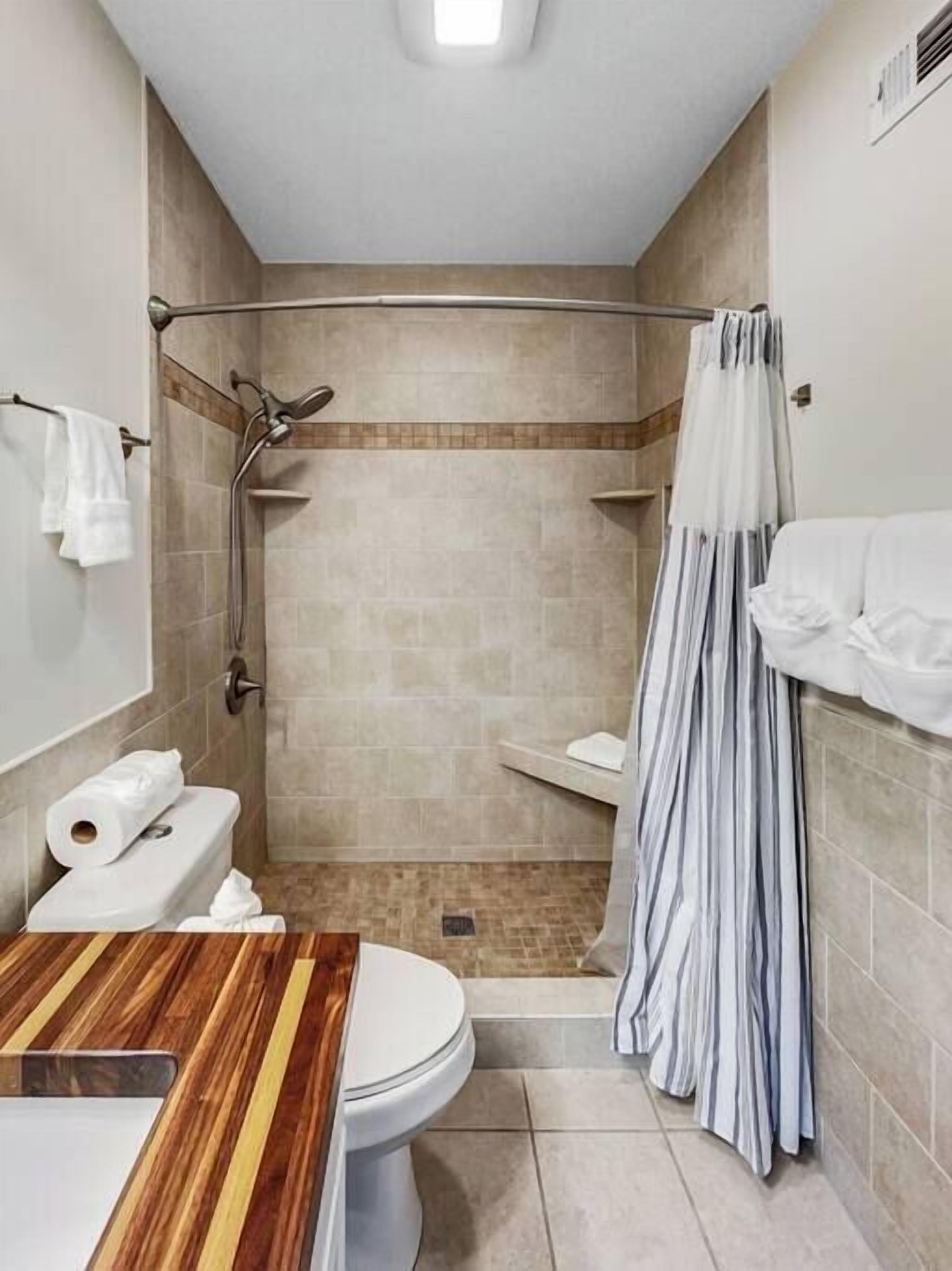 A bathroom with a shower, toilet, and sink.