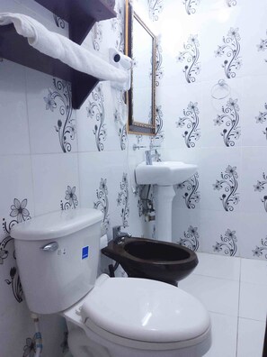 Une salle de bain comprenant des toilettes, un bidet, un lavabo et un miroir.