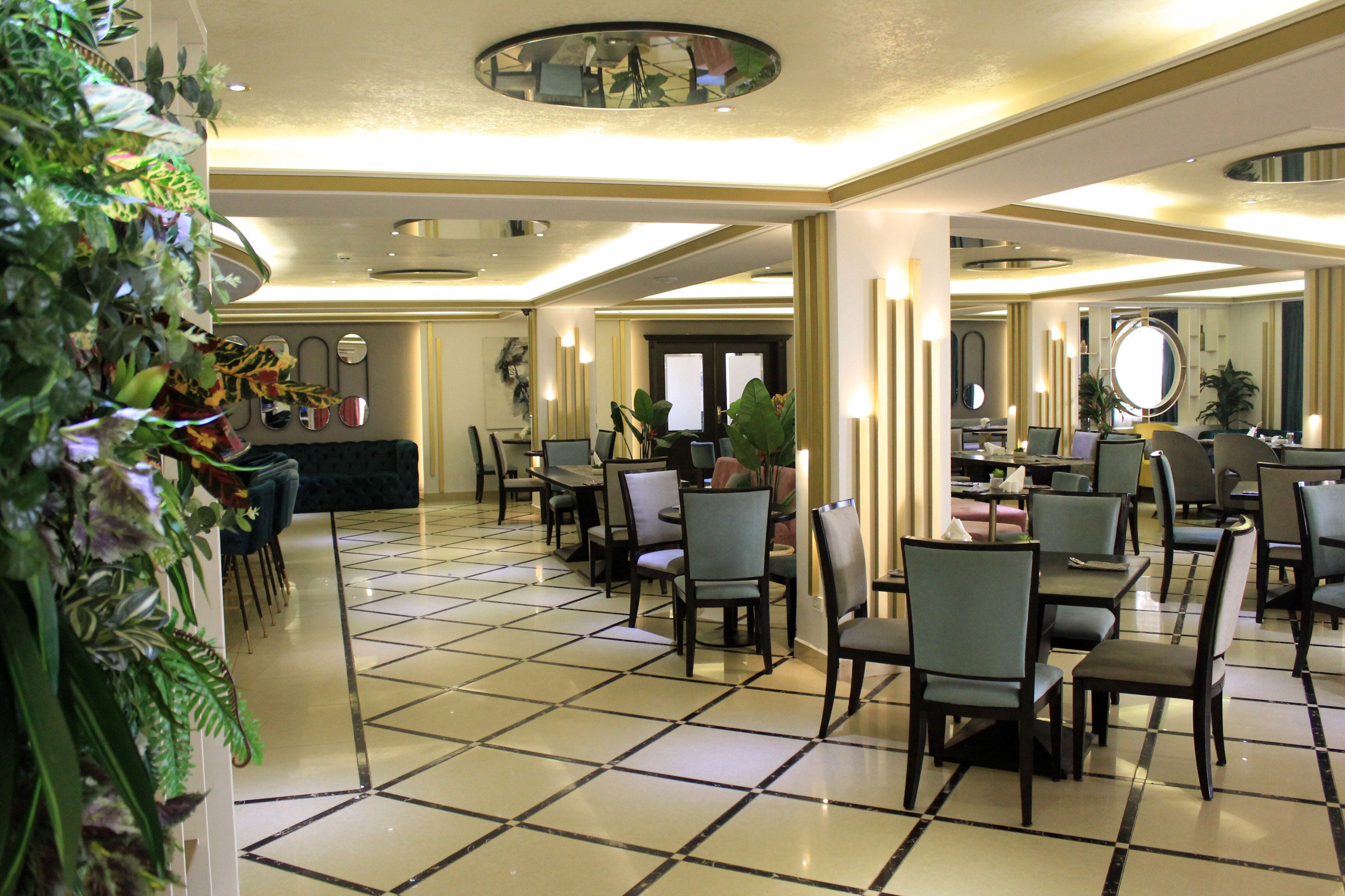 Um hall de hotel com piso de azulejos, várias áreas de estar e uma mesa de recepção.