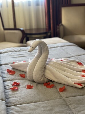 A swan-shaped towel on a bed with red rose petals scattered around. - Boulevard Palace Hotel (Monrovia)