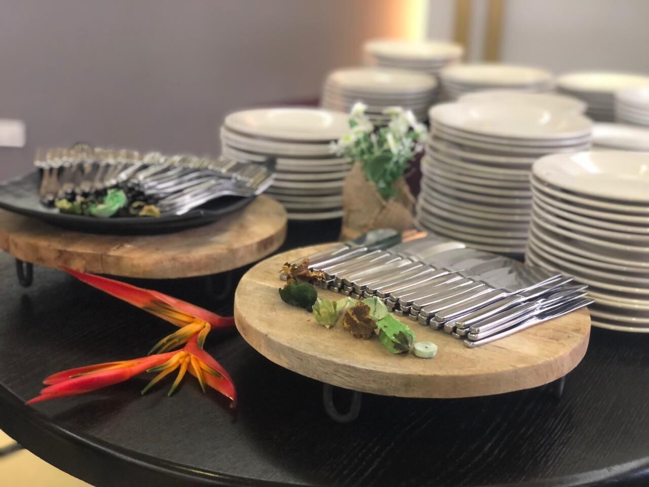 Un buffet était dressé avec plusieurs plateaux de service ronds en bois, chacun contenant des piles d’assiettes blanches et de couverts.