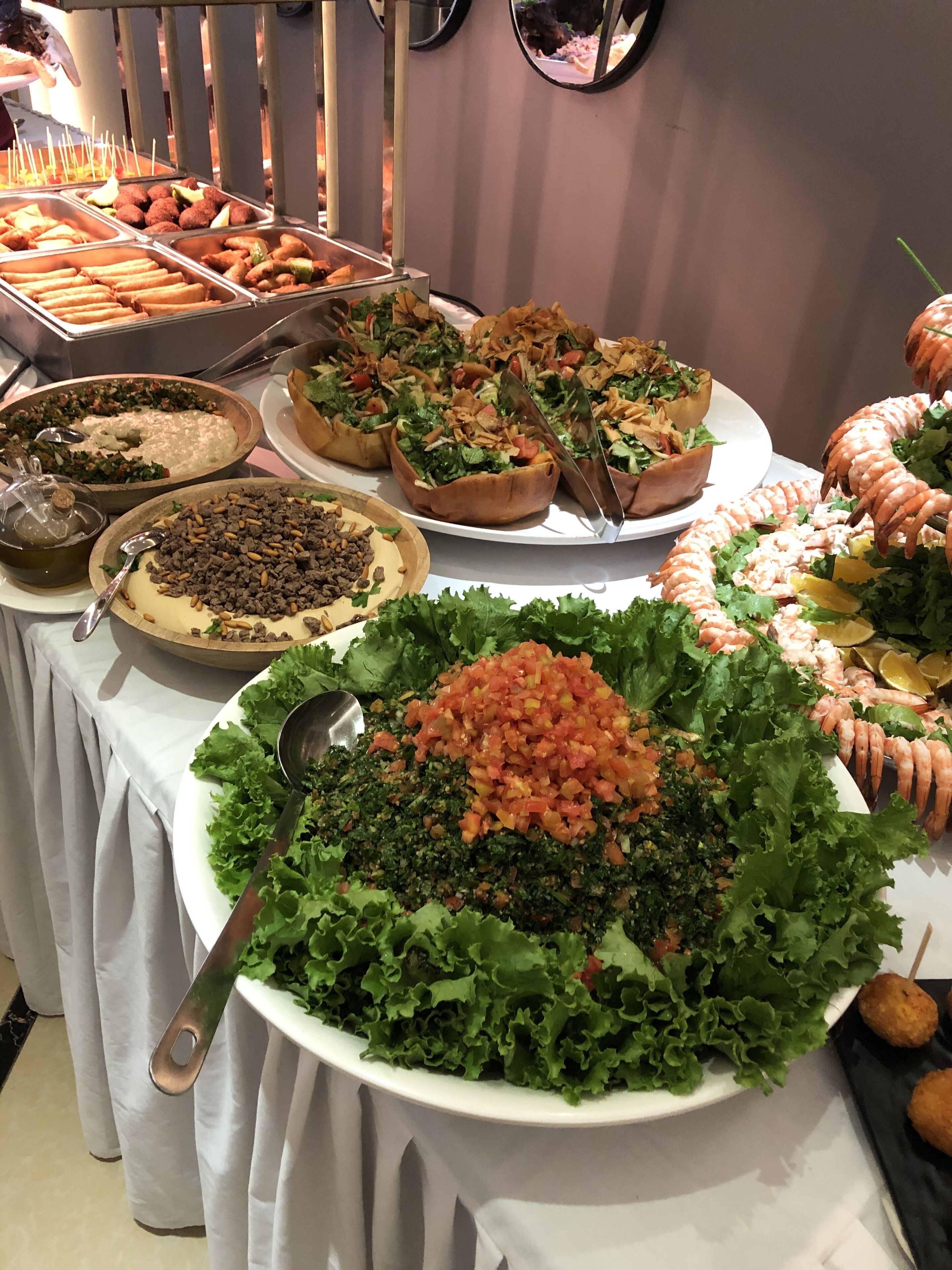 Une table de buffet proposant divers plats, notamment des salades, du pain et des fruits de mer.