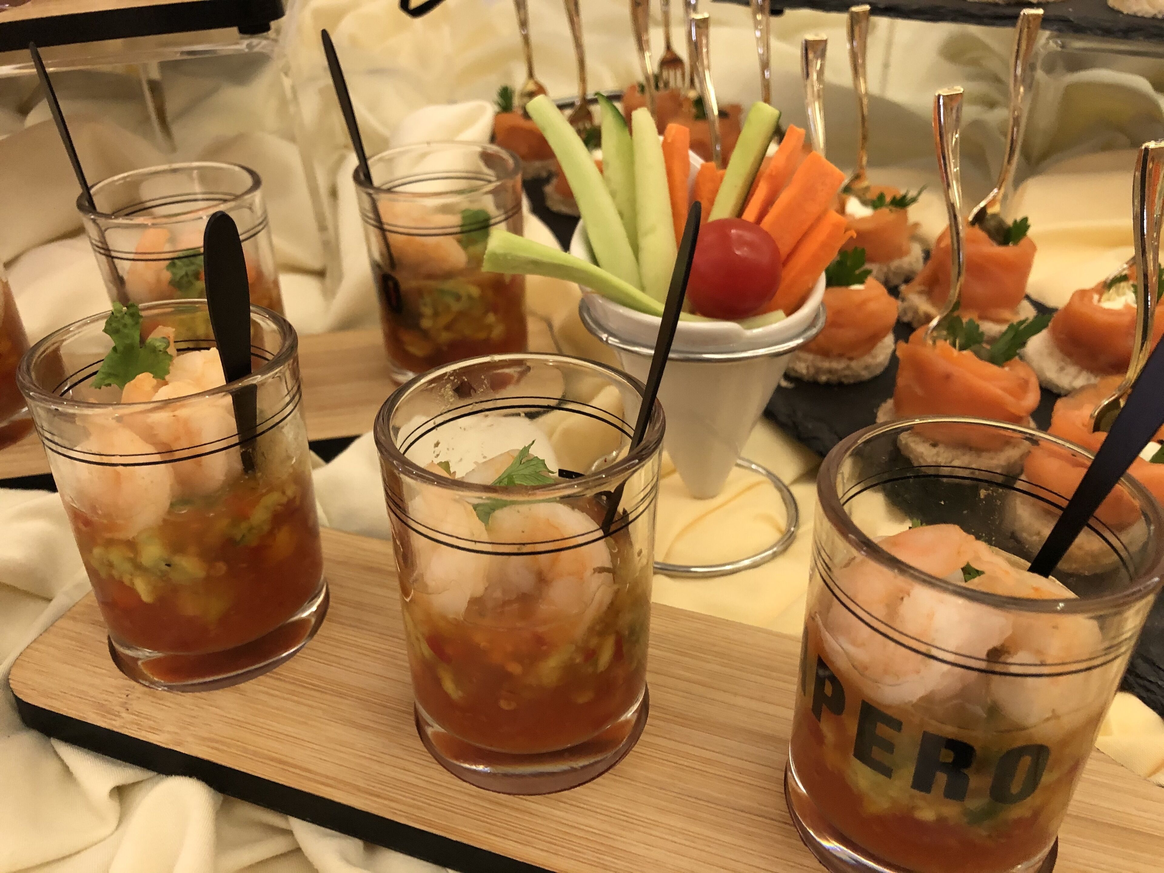 A tray with three glasses of iced drinks, a bowl of vegetables, and several appetizers.