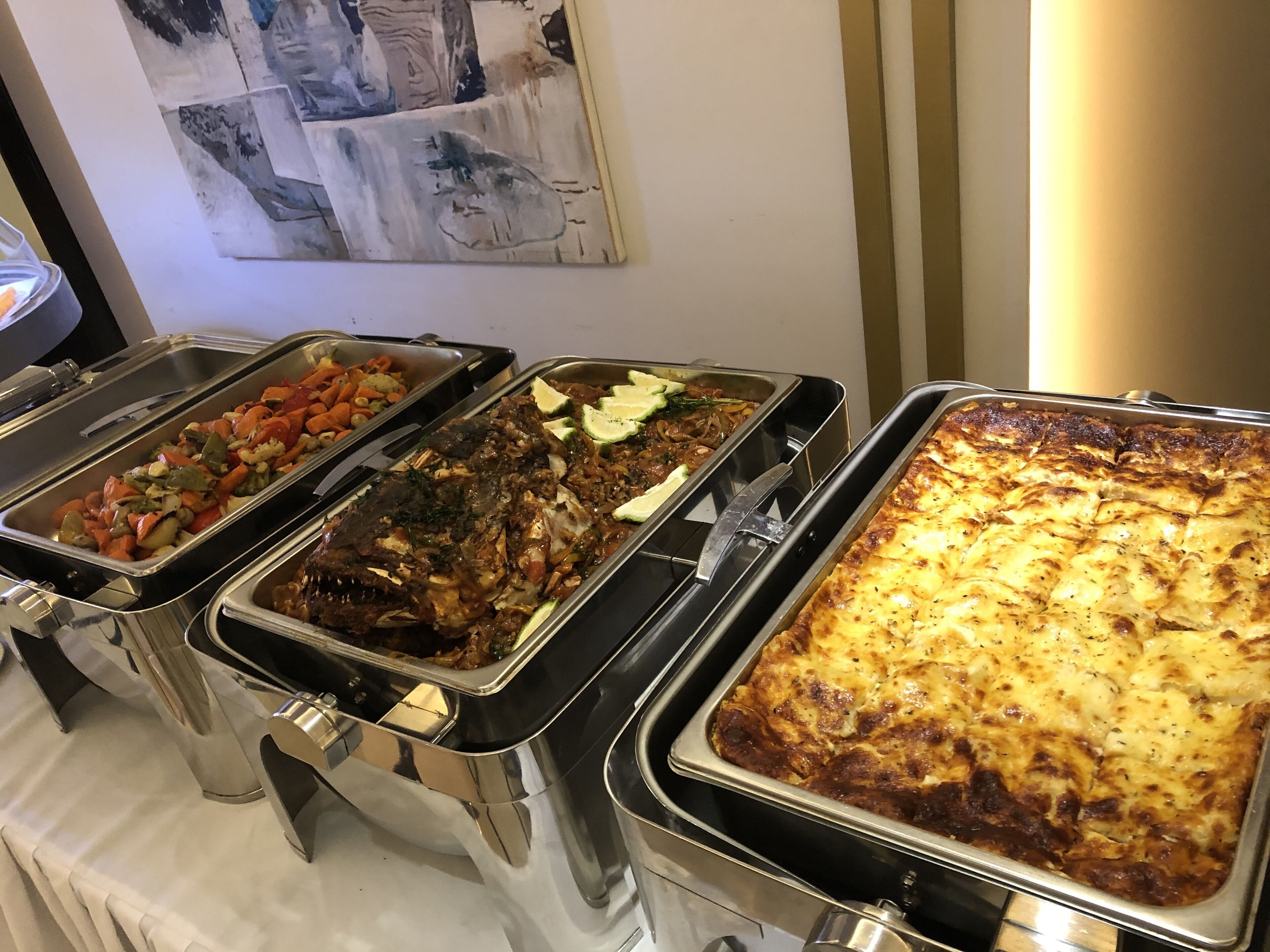 A buffet with various dishes including vegetables, a fish dish, and a baked casserole.