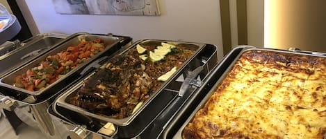 Un bufé con diversos platos, incluyendo verduras, un pescado y una cazuela al horno.