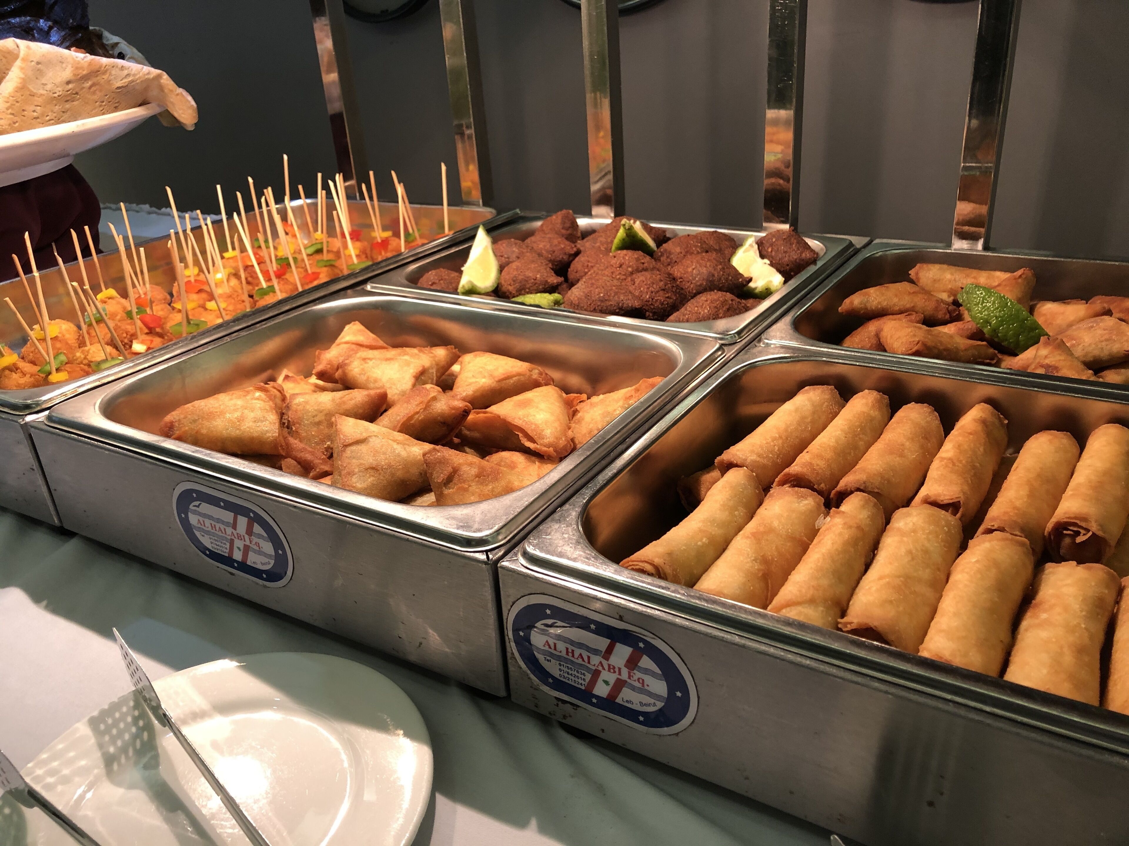A buffet with various food items including samosas and other snacks.