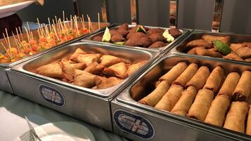 A buffet with various food items including samosas and other snacks.
