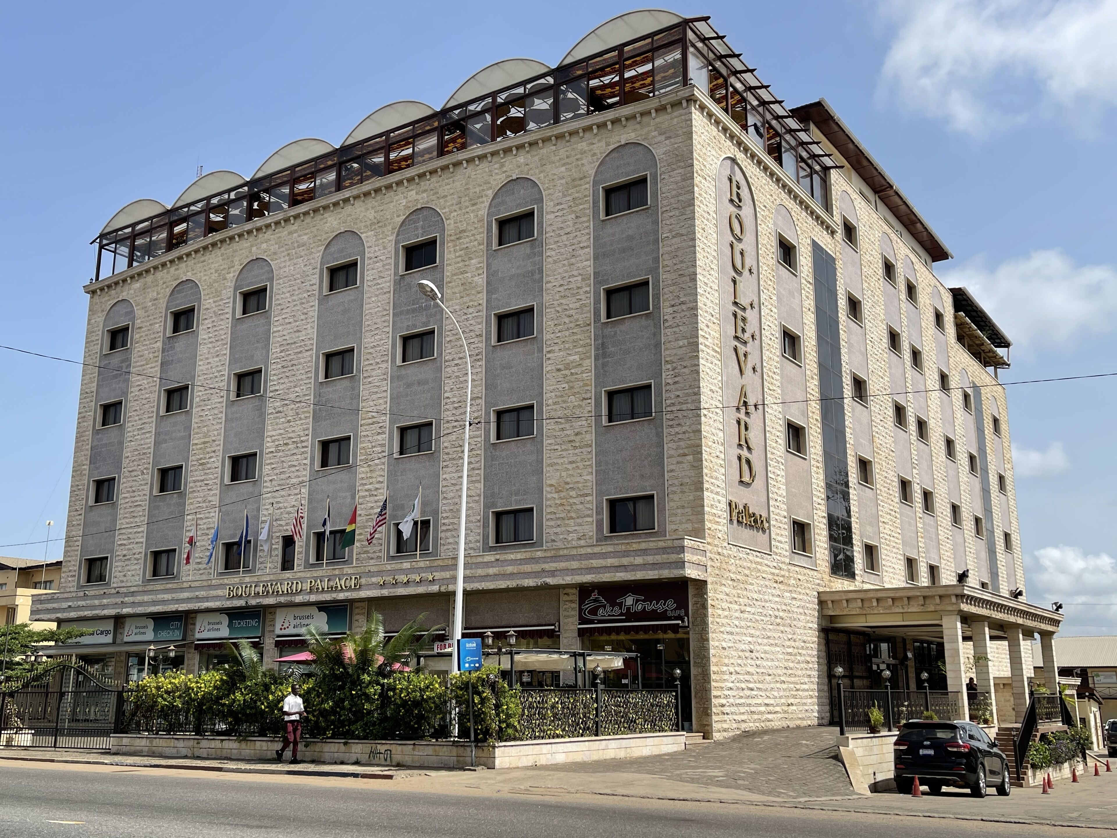 A multi-story hotel with a stone facade, multiple windows, and a balcony on the upper floor.