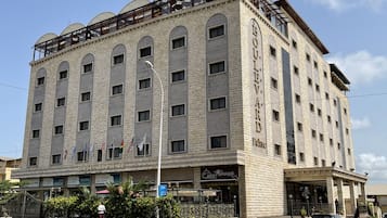 A multi-story hotel with a stone facade, multiple windows, and a balcony on the upper floor.