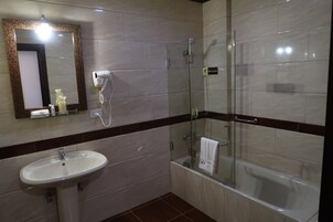 A bathroom with a sink, mirror, and glass-enclosed shower.