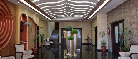 A lobby with a polished marble floor, a modern ceiling design, and seating areas.