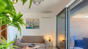 A modern living room with a sofa, a coffee table, and a painting on the wall. - Wing 77 by Interhome (Pula)