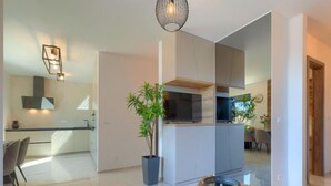 A modern kitchen with a central island, a dining area with a round table, and a living space with a sofa and a coffee table. - Wing 77 by Interhome (Pula)