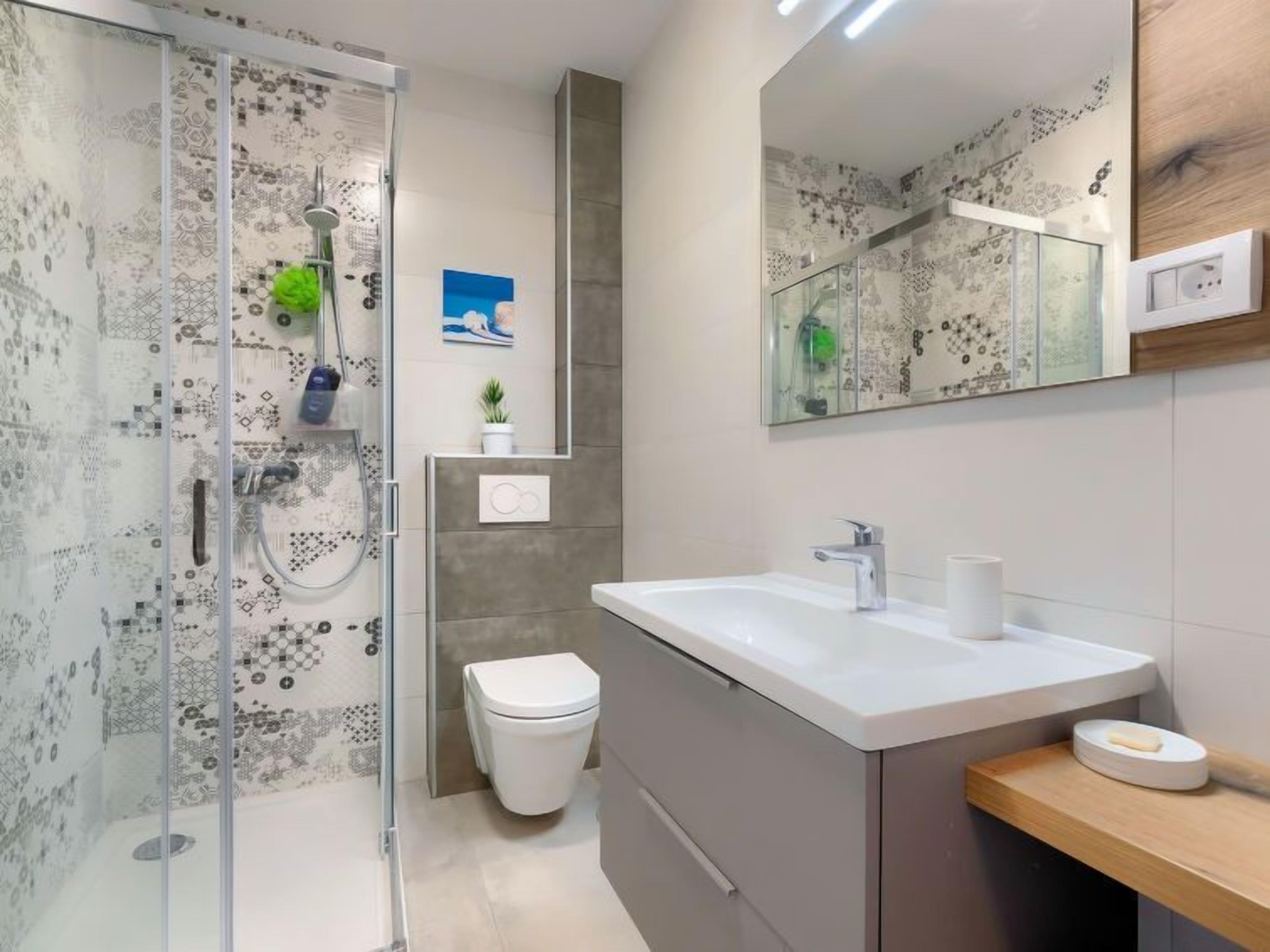Une salle de bain moderne avec une douche à parois de verre, un lavabo blanc et des toilettes.