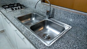 A kitchen with a stainless steel sink, granite countertop, and a gas stove. - 58th Ave. Apartment (Playa del Carmen)