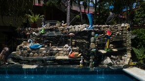Ein dekorativer Wasserteich mit Schwänen, Flamingos und einem Papagei.