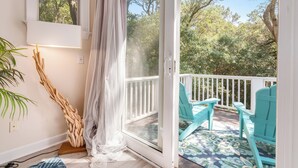 Une pièce dotée d’une porte-fenêtre coulissante qui donne sur une terrasse avec des chaises turquoise et un tapis à motifs.