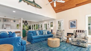 Un salon spacieux avec un canapé bleu, un tapis à motifs et un ventilateur de plafond.