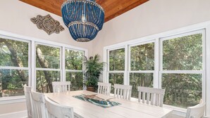 Un coin repas avec une table blanche, des chaises blanches et un lustre bleu.