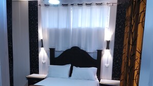 A bedroom with a large bed, two bedside tables, a ceiling fan, and a window with curtains. - Deluxe Apartment (14) RESIDENCE TROPICAL GARDEN (Boca Chica)