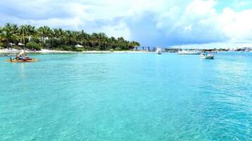 A coastal scene with clear turquoise water, a small boat, and a distant bridge.