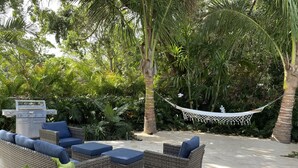 An outdoor seating area with wicker furniture and a grill.