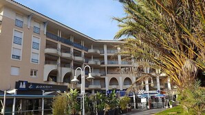 A multi-story hotel with balconies, outdoor seating, and potted plants. - Résidence Aigue Marine by Interhome (Fréjus)