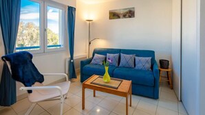 A living room with a blue sofa, a white chair, a wooden coffee table, and a floor lamp. - Résidence Aigue Marine by Interhome (Fréjus)