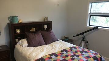 Ein Schlafzimmer mit einem Bett, einem Teleskop, einem Fenster und einem Regal mit Dekorationen.