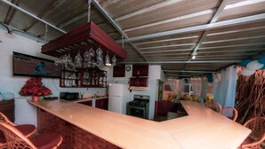 A kitchen with a long counter, wicker chairs, and hanging light fixtures. - Deluxe Apartment (7) RESIDENCE TROPICAL GARDEN (Boca Chica)