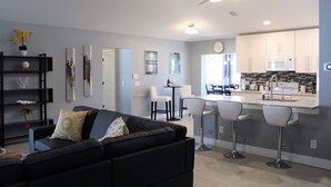 A modern kitchen with white cabinets, a microwave, and a bar area with two stools. - Newly Renovated, Beautiful Spacious House With Heated Pool. (Englewood)