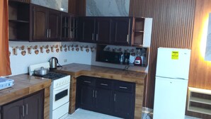 Une cuisine avec des meubles de rangement en bois foncé, un réfrigérateur blanc, une cuisinière et un four à micro-ondes.
