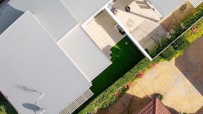A rooftop with a green lawn area, a white building, and a paved walkway.