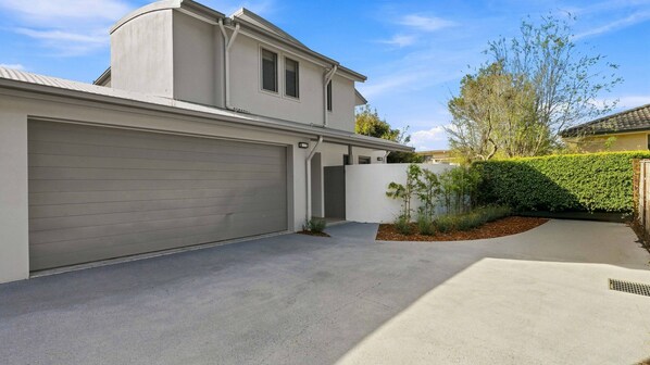 A modern two-story house with a garage, a covered driveway, and a well-maintained garden.