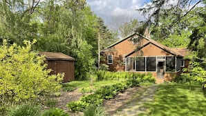 Une maison avec un jardin, un abri en bois et un chemin pavé de pierres.