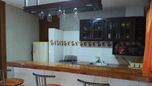 A kitchen with a central island, bar stools, a refrigerator, cabinets, and a stove.