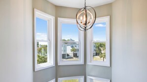 A room with four windows and a chandelier. - Cute Family Beach Home in Wild Dunes Resort; Close to the Beach w/Porch Swing & Community Pool! (Isle Of Palms)