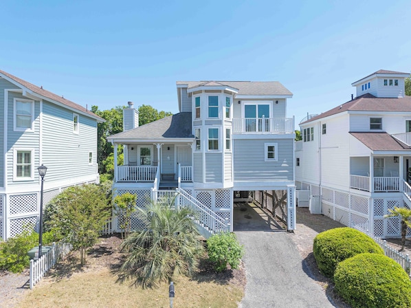 A two-story house with a covered porch and a small balcony. - Cute Family Beach Home in Wild Dunes Resort; Close to the Beach w/Porch Swing & Community Pool! (Isle Of Palms)
