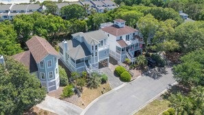 A coastal residential area with multiple houses, including a prominent two-story house with a balcony and a garage. - Cute Family Beach Home in Wild Dunes Resort; Close to the Beach w/Porch Swing & Community Pool! (Isle Of Palms)