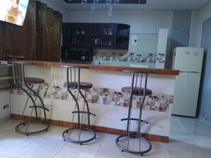 Una cocina con barra, que incluye taburetes y un refrigerador.