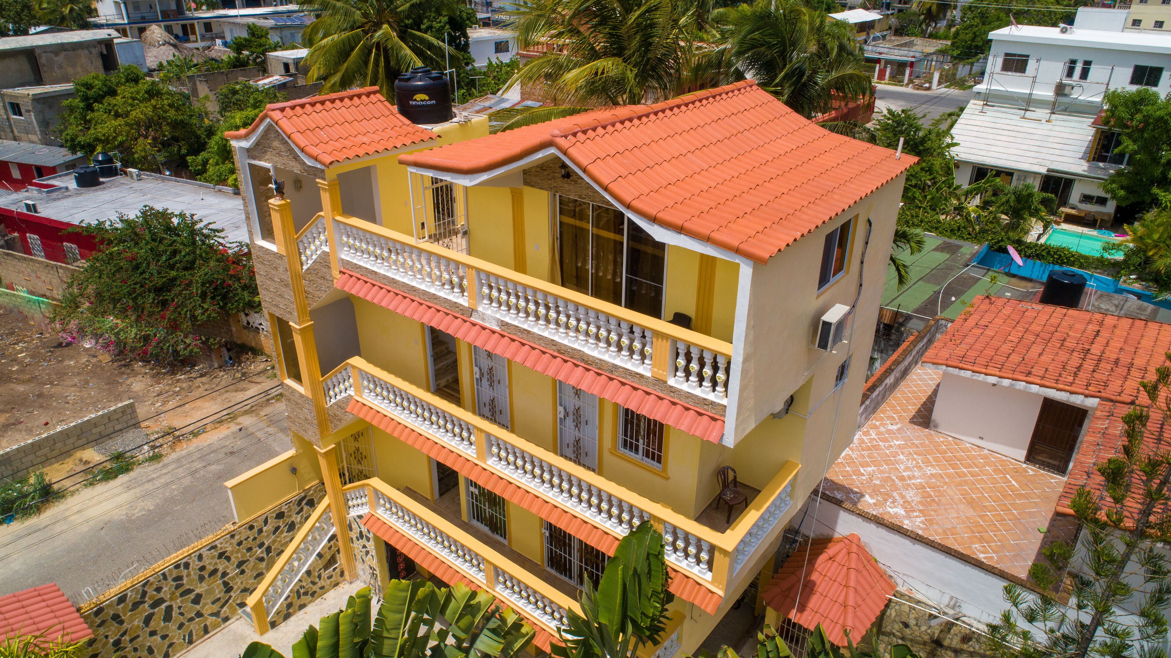 Un edificio de varios pisos con balcones, techo de tejas y un depósito de agua en la azotea.