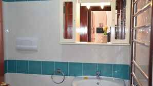A bathroom with a sink, a mirror, and a towel rack. - The House in Sardinia Holiday Apartment (Olbia)
