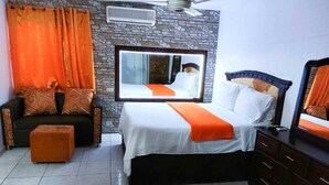Een hotelkamer met een bed, een bank, een klein voetenbankje, een dressoir en een spiegel.
