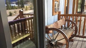 A wooden deck with a rustic chair and a window overlooking a mountainous landscape.