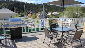 A deck with a grill, outdoor seating, and a view of houses and mountains. - Downtown Jasper Suite Beautiful Views (Jasper)