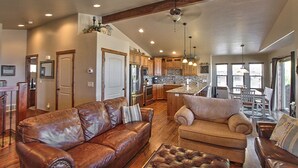 A spacious living room with leather sofas, a fireplace, and a kitchen area with wooden cabinets and a central island. - Private beach, pools/hot tub, winter sports, sleeps 20 (Fish Haven)