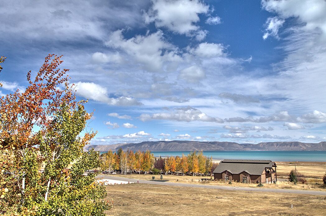 A rural landscape with a clear sky, a lake, and a building with a sloped roof.