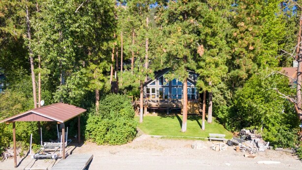A lakeside cabin with a dock, surrounded by dense trees.