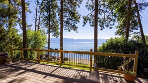 A wooden deck with a yellow railing overlooking a lake, surrounded by trees.